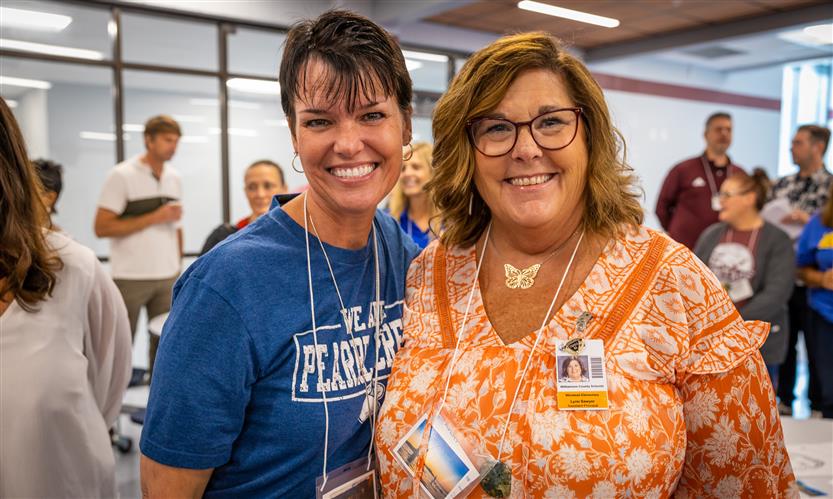 Two administrators stand together and smile